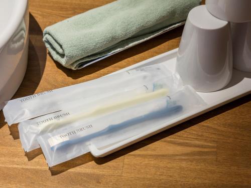 two toothbrushes in a plastic wrapper on a table at Shiretoko Yuhi No Ataruie Onsen Hostel in Shari