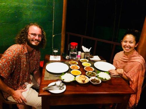 a man and woman sitting at a table with food at Chena Huts Eco Resort in Sigiriya