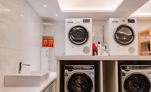 a laundry room with three washing machines and a sink at Paco Hotel Guangzhou Zoo Metro Branch in Guangzhou