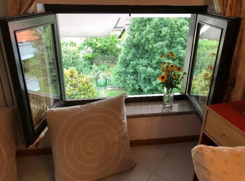 a pillow sitting in front of a window with flowers at La mansarda di Orni in Ivrea