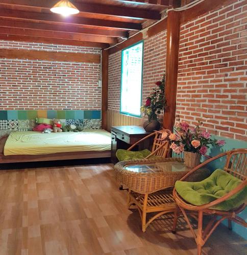 a room with a bed and chairs and a brick wall at Tien Yoga House in Cái Bè