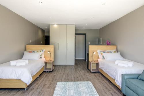 a bedroom with two beds and a blue couch at Sky Blue Guest House in Kenton on Sea