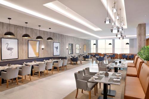 a restaurant with tables and chairs in a room at voco Al Khobar by IHG in Al Khobar