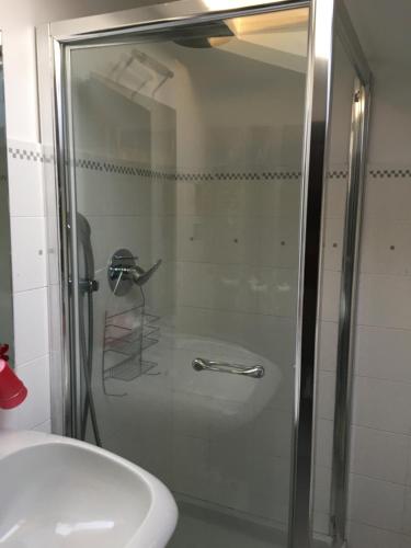 una ducha con una puerta de cristal junto a un lavabo en La mansarda di Orni, en Ivrea