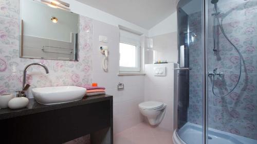 a bathroom with a sink and a toilet and a shower at Charming villa Bea with private pool and volleyball in Koromačno