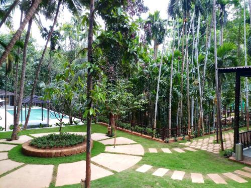 a garden with palm trees and a pool at Stone Wood Nature Resort, Gokarna in Gokarn