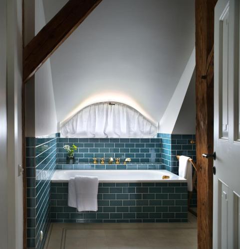 a bathroom with a tub with blue tile at Bethlen Estates Transylvania in Daneş