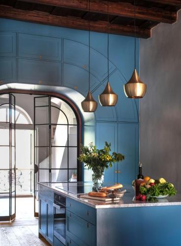 a kitchen with blue cabinets and pendant lights at Bethlen Estates Transylvania in Daneş