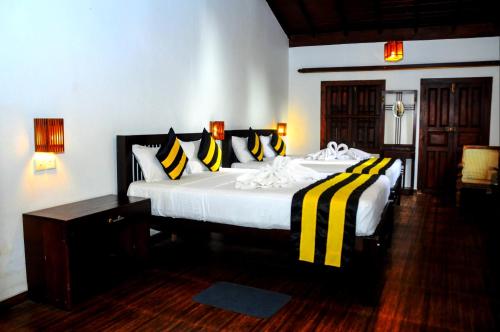 a bedroom with a large bed with yellow and black pillows at Happy Banana Hotel in Unawatuna
