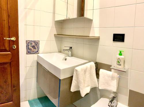 uma casa de banho branca com um lavatório e toalhas em Balcone sulle Meraviglie em Urbino
