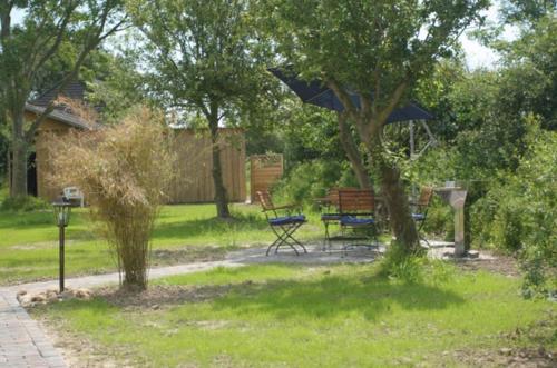 a park with a bench and a table with an umbrella at Ferienhaus Deichgraf in Vollerwiek