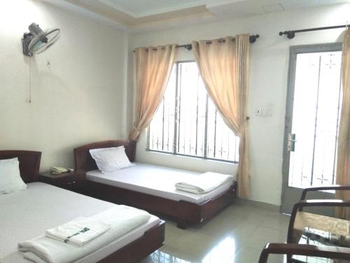 1 Schlafzimmer mit 2 Betten und 2 Fenstern in der Unterkunft Trường Chính Sách Công Và Phát Triển Nông Thôn in Ho-Chi-Minh-Stadt