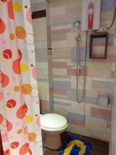 a bathroom with a shower with a toilet and a shower curtain at Orange Mangrove Pension House by SMS Hospitality in Puerto Princesa City