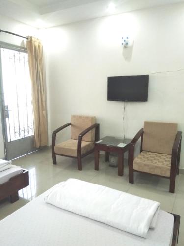 Zimmer mit einem Bett, 2 Stühlen und einem TV in der Unterkunft Trường Chính Sách Công Và Phát Triển Nông Thôn in Ho-Chi-Minh-Stadt