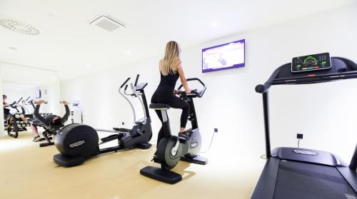 a woman riding on an exercise bike in a gym at One Suite Hotel in Mlini