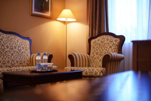 a hotel room with two chairs and a table with water bottles at LOTTE City Hotels Tashkent Palace in Tashkent
