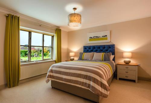 a bedroom with a bed with a blue headboard and a window at Bramble Lodge in Blakeney