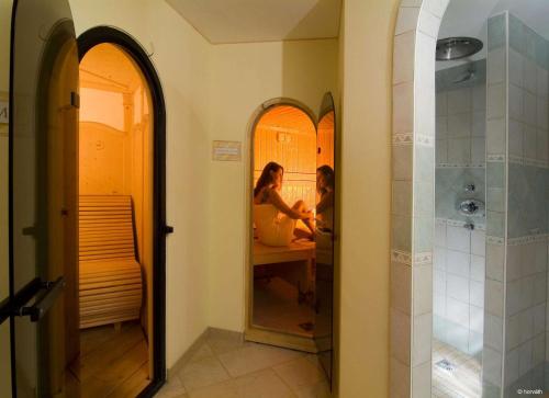 twee mensen spiegelen in een badkamer bij Alpenhof Brixen in Brixen im Thale