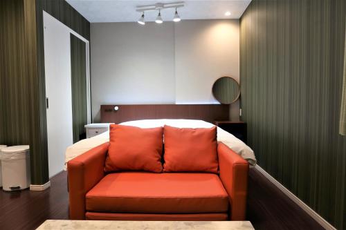 - un canapé orange dans une chambre avec un lit dans l'établissement 玉出104 wifi付 玉出駅から徒歩2分 地下鉄難波迄8分, à Osaka