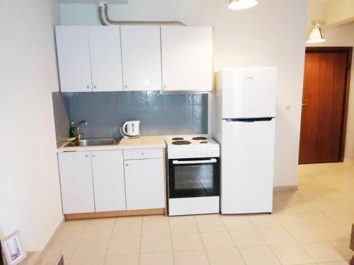 a kitchen with white cabinets and a white refrigerator at New Times Home&Suites in Athens