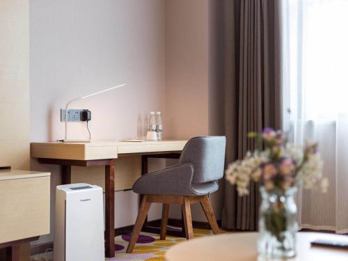 a room with a desk and a chair and a table at Echarm International Hotel Guangzhou Baiyun International Airport Huadu Plaza Branch - Free Deliver Service to Guangzhou Baiyun International Airport & Free Deliver Service to Canton Fair Complex During Canton Fair Period in Huadu