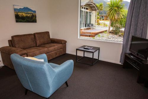 a living room with a couch and a chair and a television at Franz Alpine Retreat in Franz Josef