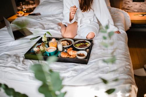 a woman sitting on a bed with a tray of food at One Suite Hotel in Mlini