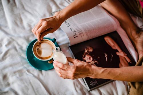 a woman holding a cup of coffee and a magazine at One Suite Hotel in Mlini