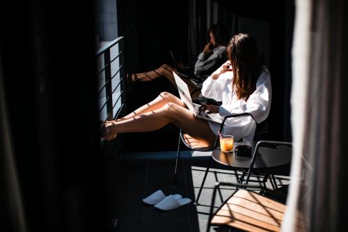 a woman sitting on a balcony talking on a cell phone at One Suite Hotel in Mlini