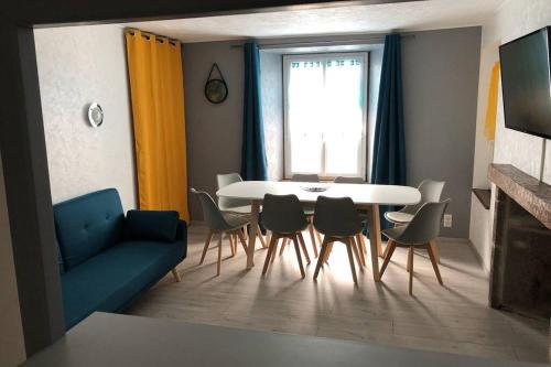 sala de estar con sofá azul, mesa y sillas en Joli appartement à Murat proche du Lioran Cantal en Murat