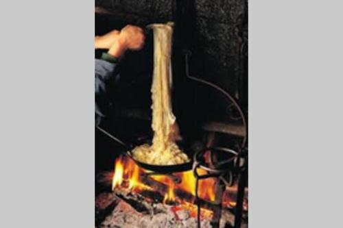 a man standing over a fire in a stove at Joli appartement à Murat proche du Lioran Cantal in Murat