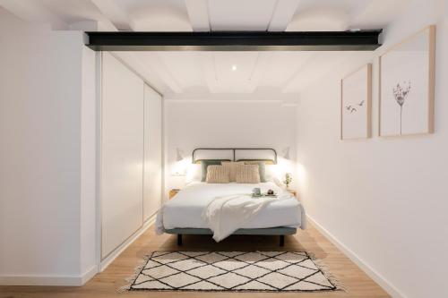 1 dormitorio con 1 cama en una habitación blanca en Aspasios Verdi Apartments en Barcelona