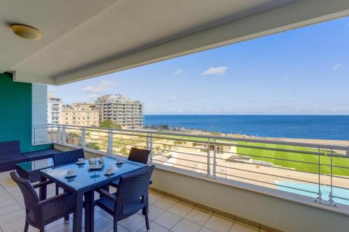 balcone con tavolo, sedie e vista sull'oceano di Seafront Apartment Sliema a Sliema