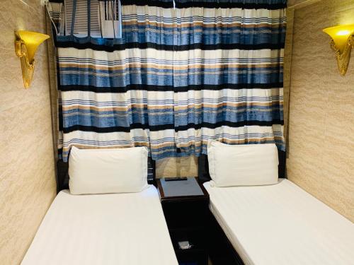 two beds in a small room with a curtain at Sleep Inn in Hong Kong