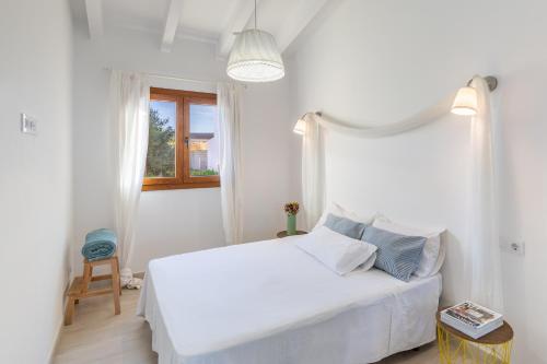 a white bedroom with a white bed and a window at Viles Can Moreno in Ses Salines
