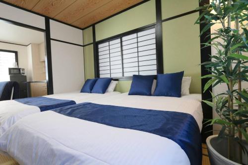 大阪市にあるLiz3 Guest House Liz Nakazakichoのベッドルーム1室(青い枕のベッド2台付)