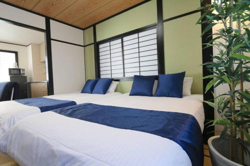 a bedroom with two beds with blue pillows at Liz3 Guest House Liz Nakazakicho in Osaka