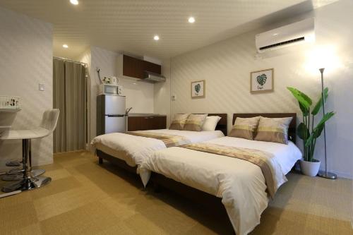 a bedroom with two beds and a table and a refrigerator at NK3 Elizabeth Garden Kurosaki in Osaka