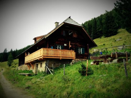 een groot houten huis op een heuvel met een veranda bij Rettlhof in Sankt Peter am Kammersberg