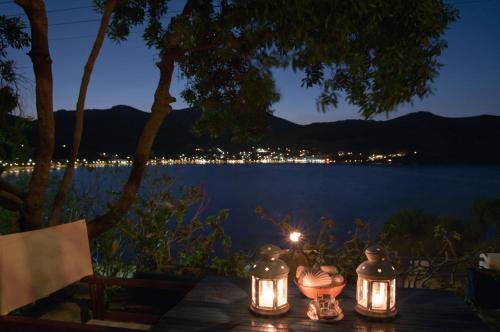 a table with candles and a view of a lake at night at Antoniadi Rooms in Livadia