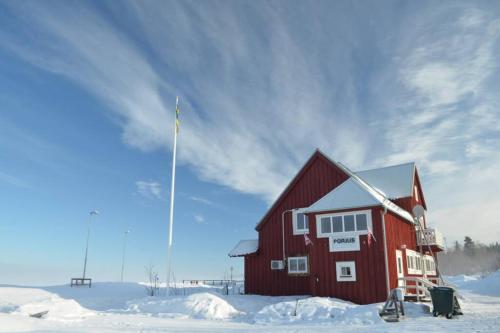 une grange rouge dans la neige avec un drapeau dans l'établissement Arctic Colors Northern Lights Apartments, à Porjus