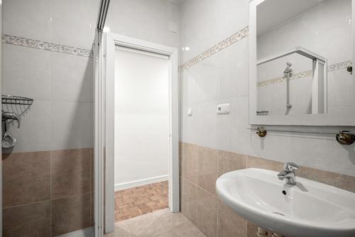 uma casa de banho com um lavatório e um chuveiro com um espelho. em Espacioso, Moderno y a pie de Playa Zurriola em San Sebastián