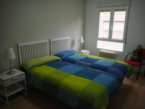 a bedroom with a colorful bed and a window at Apartamento El Ayuntamiento de Logroño in Logroño