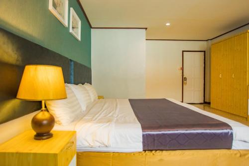 a bedroom with a bed with a lamp on a table at Pro Andaman Place in Karon Beach