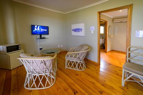a living room with two chairs and a tv on the wall at Sangiro Game Lodge in Bloemfontein