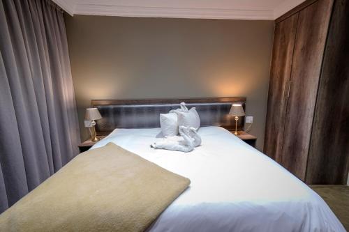 a bedroom with a bed with white sheets and pillows at Sangiro Game Lodge in Bloemfontein