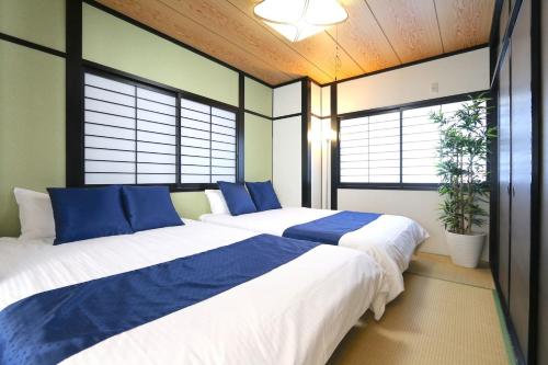 two beds in a room with two windows at Liz3 Guest House Liz Nakazakicho in Osaka