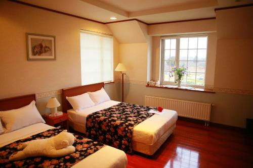 a hotel room with two beds and a teddy bear on the bed at Agri In Holiday in Hirosaki