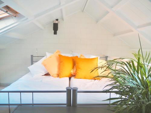 a bed with yellow and white pillows on it at Studio ter Duyn in Ouddorp