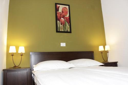 a bedroom with a bed and two lamps and a painting at La Livada in Otopeni